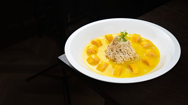 Precisely plated modern dish with saffron sauce and a crisp noodle garnish.