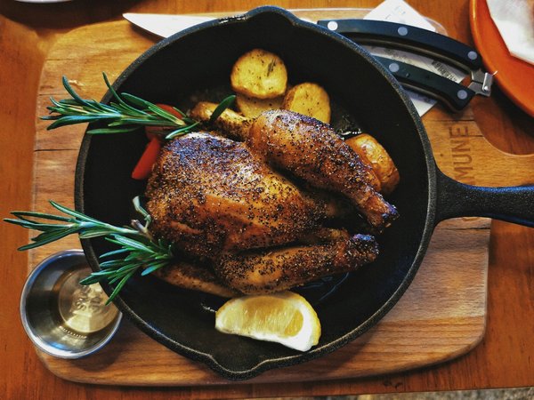 Golden roasted chicken with rosemary and potatoes served in a cast-iron pan.