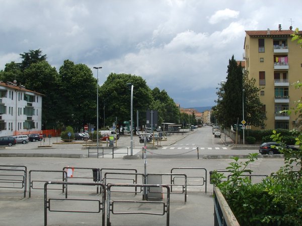 Vista di una strada nel quartiere Isolotto a Firenze, con edifici residenziali e viali alberati.