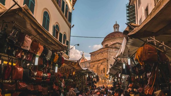 San Lorenzo Market in Florence with leather bag stalls and the Basilica of San Lorenzo in the background.