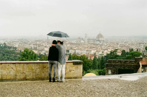 Couple under an umbrella with a view of the Florence Cathedral on a cloudy day.