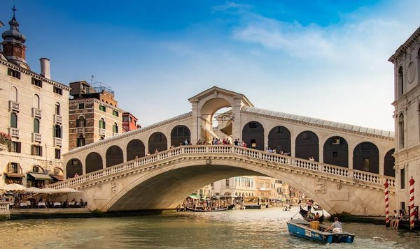 Ponte di Rialto sul Canal Grande a Venezia con gondole e ristoranti lungo il canale.