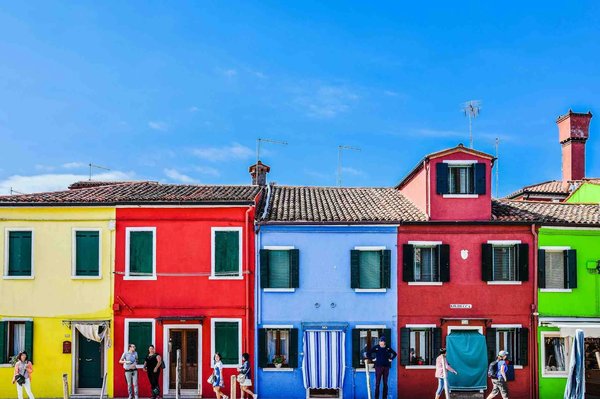 Case colorate di Burano con cielo blu, simbolo iconico di Venezia durante il tour natalizio.