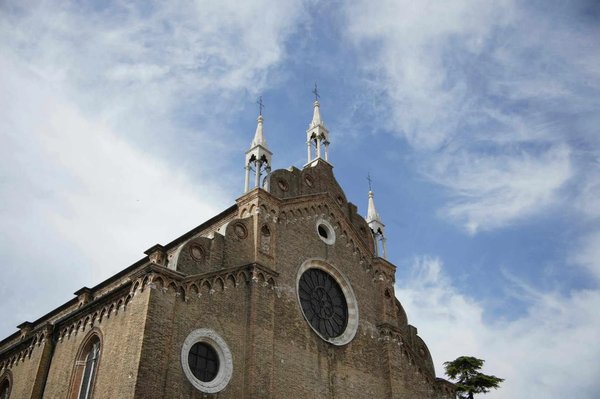 Facciata della Chiesa dei Frari a Venezia con cielo azzurro e dettagli architettonici gotici.