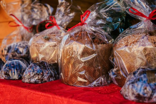 Panettoni e pandori incartati e legati con un nastro rosso, pronti per Natale.