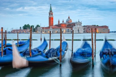 Moored gondolas with a view of San Giorgio Maggiore Church in Venice at sunset.