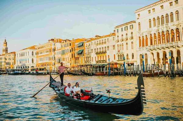 Gondola at sunset on the Grand Canal in Venice with historic buildings in the background.