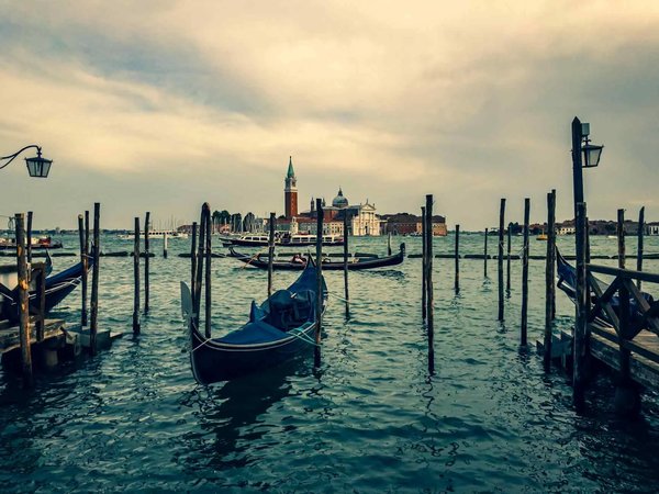 Sunset on San Giorgio Maggiore Island in Venice with gondolas and calm water.