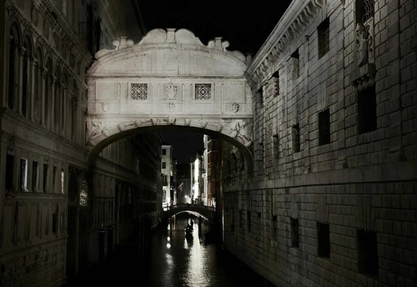 Bridge of Sighs in Venice illuminated by moonlight, with reflections on the water and a suggestive nighttime atmosphere.