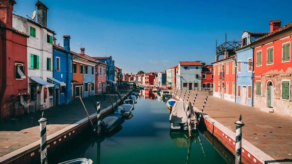 Colorful houses and canal with boats on the island of Burano, Venice, on a sunny day.