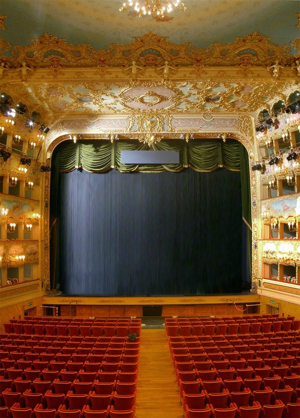 Interior of Teatro La Fenice in Venice, showing tiers of gilded boxes and red velvet seating facing the stage.