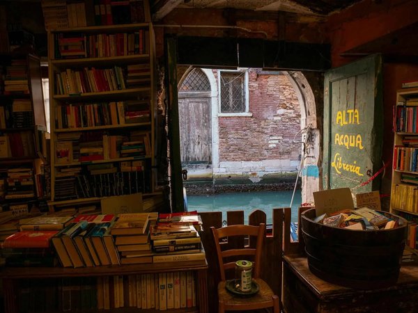 Interior of Libreria Acqua Alta in Venice with a view of the canal and shelves full of books.