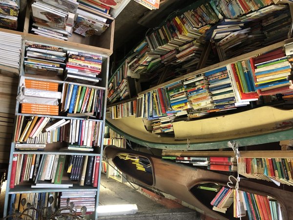 Interior of Libreria Acqua Alta in Venice, with books stacked in a gondola and on overflowing shelves.