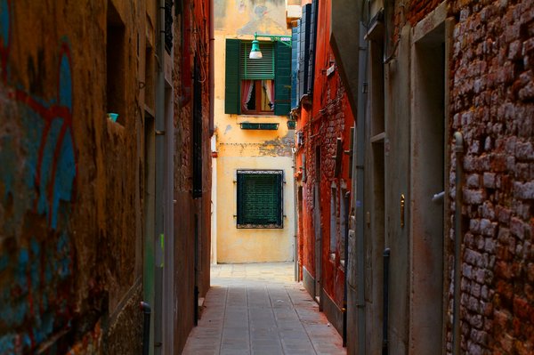 An empty narrow calle in Venice's Cannaregio district, lit by early morning light.