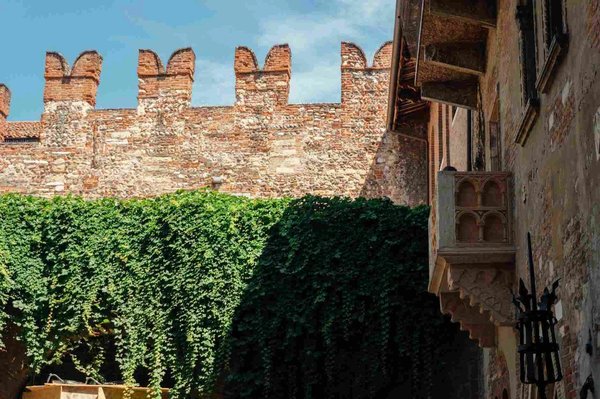 Juliet's Balcony in Verona with medieval walls and green ivy.