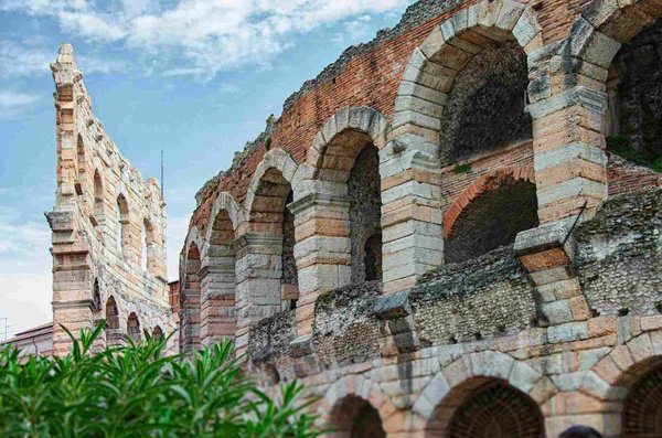 Close-up view of Verona's Roman Arena with stone arches and blue sky in the background.