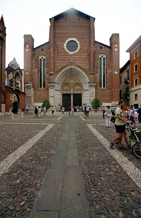 Unfinished brick facade of the Basilica of Sant'Anastasia in Verona, with its Gothic portal and rose window.