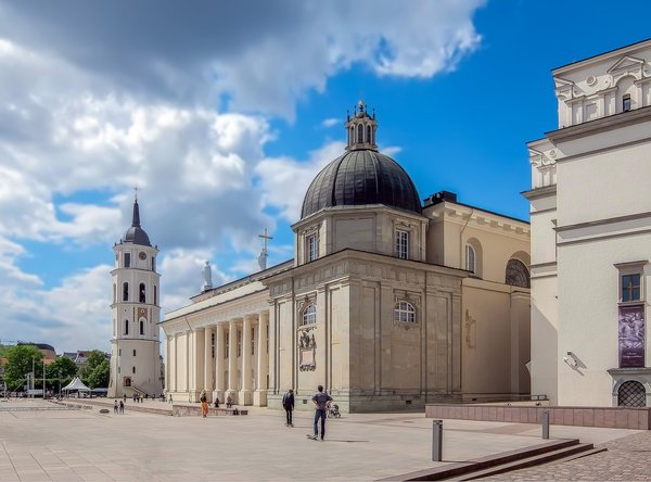 Cattedrale di Vilnius e torre campanaria con cielo blu e persone nella piazza.