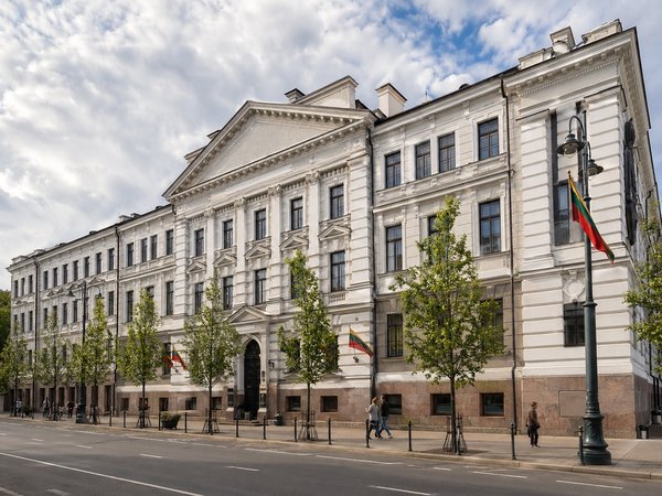 Facciata del Museo delle Occupazioni e delle Lotte per la Libertà a Vilnius con bandiere lituane e cielo sereno.