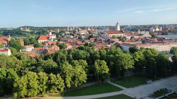 Panoramic view of Vilnius with historic buildings and green trees in the foreground.