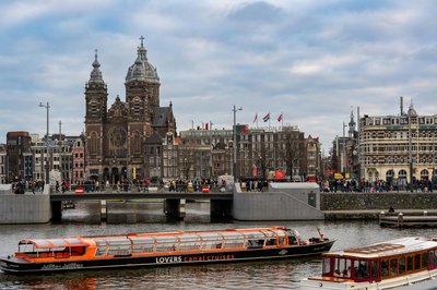 Basilica of Saint Nicholas and canal boats in Amsterdam, with historic buildings in the background.