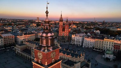 Aerial view of Krakow at sunset featuring St. Mary's Basilica and the Town Hall Tower in the Main Market Square.