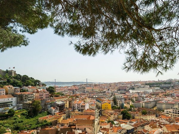 Panoramic view of Lisbon from Miradouro da Senhora do Monte with rooftops, Tagus River, and bridge in the background.