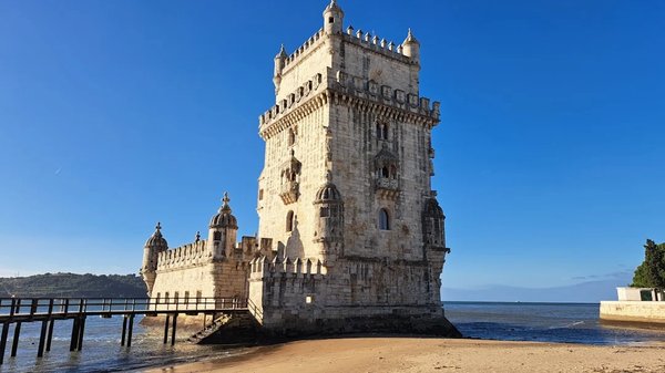 Belém Tower in Lisbon with blue sky and sea reflections.