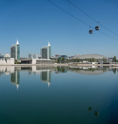 Panoramic view of Lisbon with the Vasco da Gama Tower, cable cars, and water reflections in the Parque das Nações district.