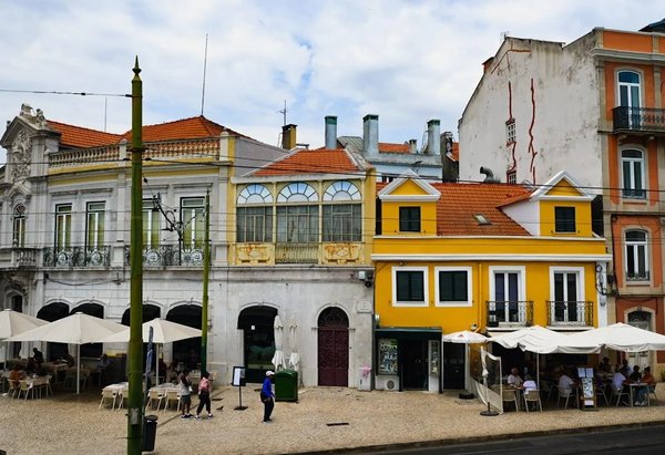 Street with colorful buildings and outdoor tables, possible local market scene in Lisbon.