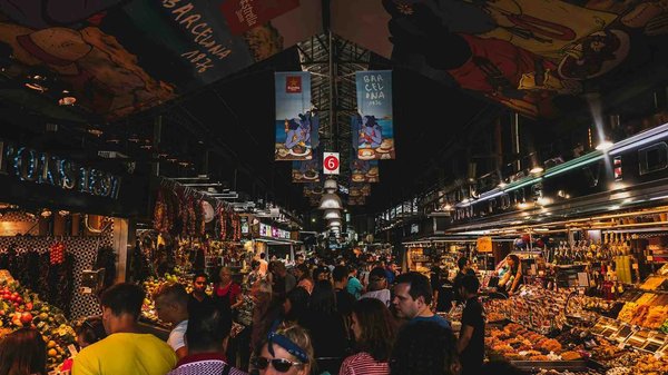 La Boqueria Market in Barcelona with colorful stalls and a crowd of visitors.