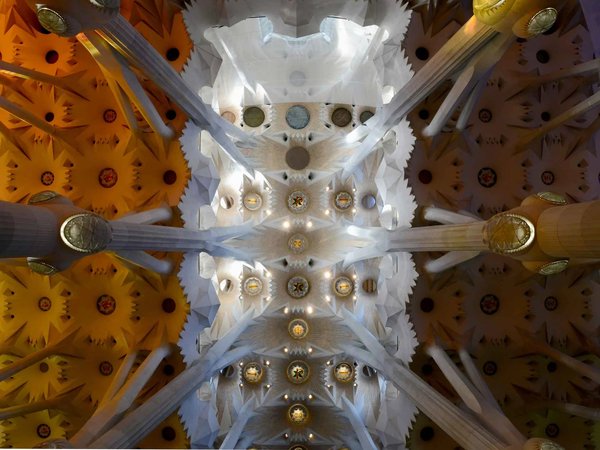 Interior of the Sagrada Familia in Barcelona with decorated ceiling and illuminated columns.