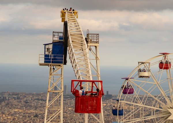 Colorful gondola cars of the Tibidabo Ferris wheel, with Barcelona's coastline stretching out below.