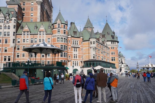View of Château Frontenac and Terrasse Dufferin in Quebec City with tourists strolling.