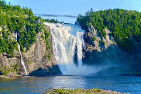 Montmorency Falls with suspension bridge and lush vegetation, Quebec, Canada.
