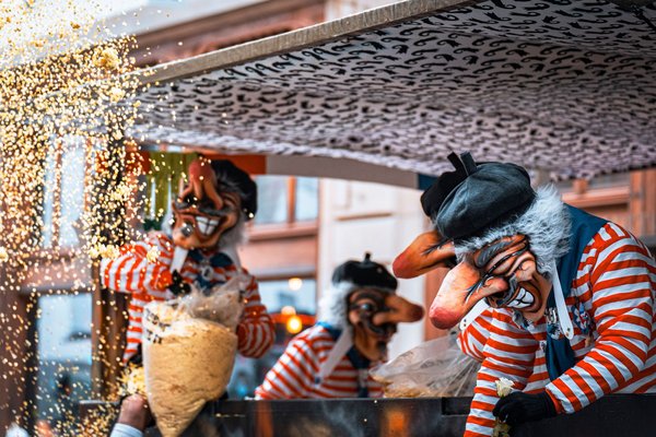 Masked characters in colorful costumes with sparks flying during a carnival event in Quebec.