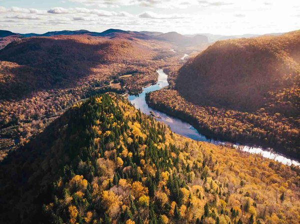 Aerial view of Jacques-Cartier National Park in Quebec with hills, river, and vibrant fall colors.