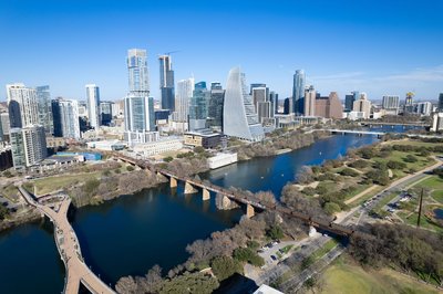 Panoramic view of Austin skyline with Colorado River and bridges on a sunny day.