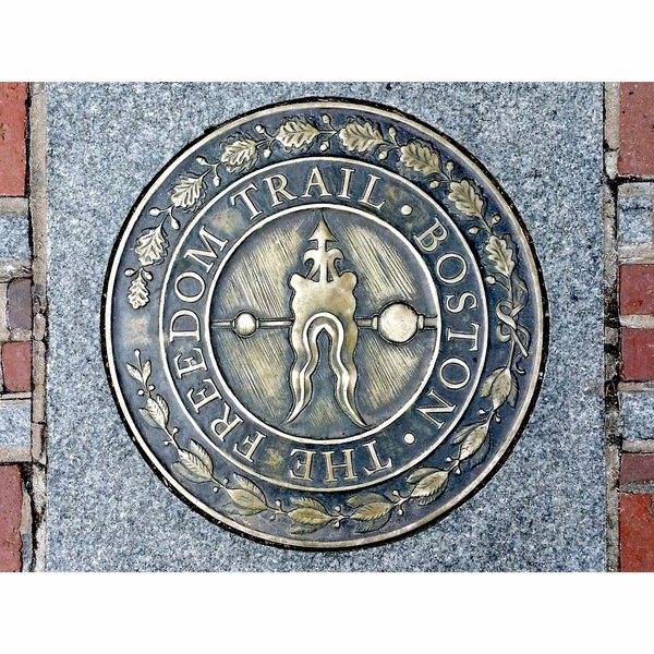 Close-up of the Freedom Trail marker in Boston, engraved on a bronze plaque set into a sidewalk.