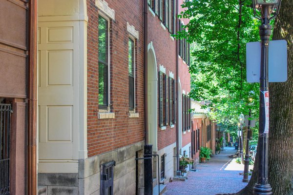 Beacon Hill street in Boston with red brick buildings, gas lamps, and cobblestone sidewalks.