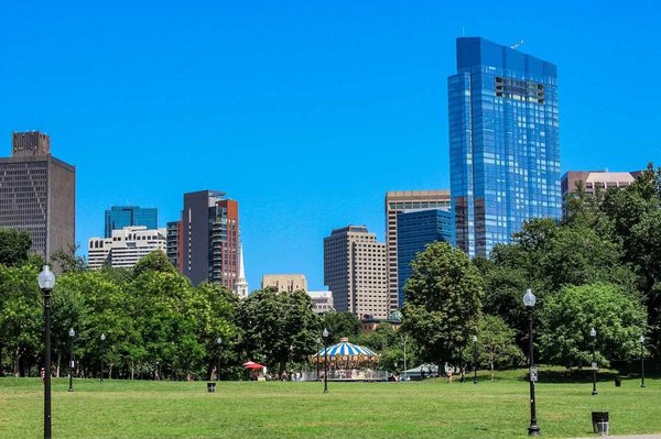 View of Boston Common with skyscrapers in the background and a bright blue sky.