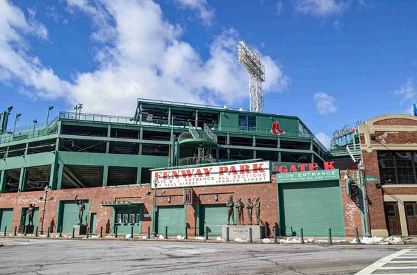 Entrance to Fenway Park in Boston with a blue sky and statues in front.