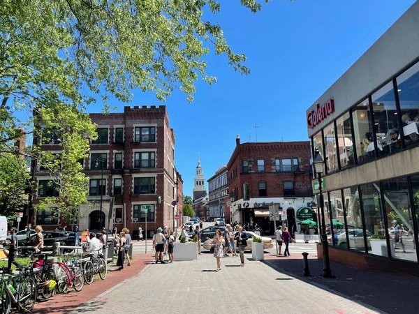 Pedestrian street in Boston with historic buildings, parked bicycles, and people strolling on a sunny day.