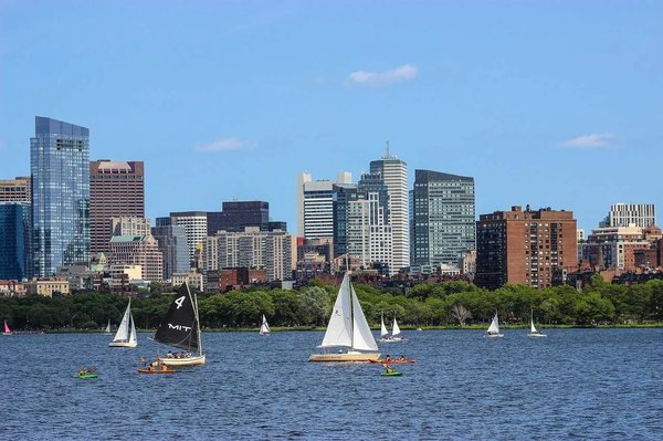 View of the Charles River with sailboats and Boston skyline, iconic spot for outdoor activities.