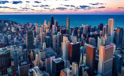 Panoramic view of Chicago skyline with iconic skyscrapers and Lake Michigan at sunset.