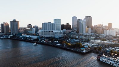 Panoramic view of New Orleans skyline with the Mississippi River and Natchez steamboat at sunset.