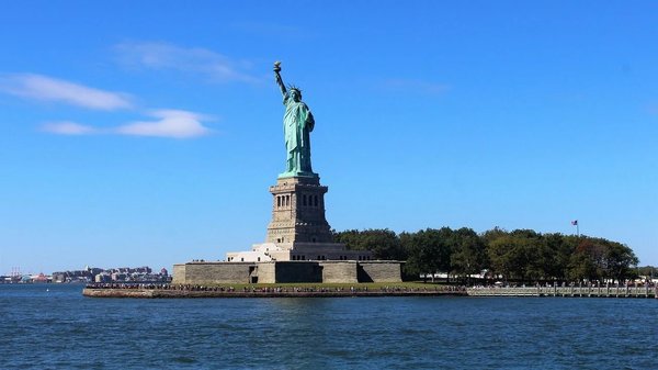 Statua della Libertà a New York vista dal mare con cielo blu e dettagli nitidi.