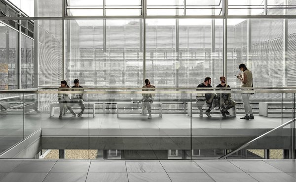 Interno moderno del MoMA con persone sedute su panche e pareti in vetro e metallo.