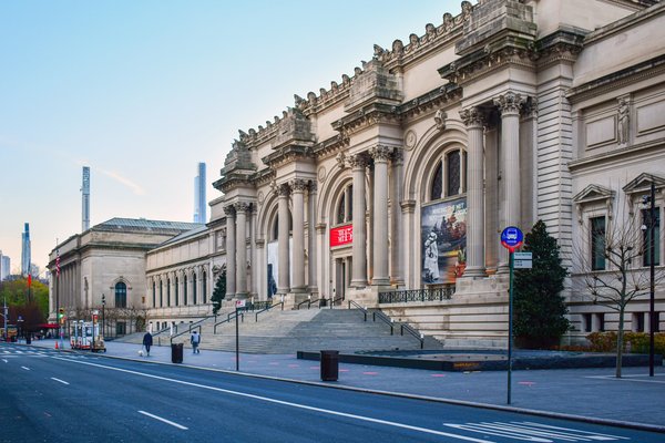 Facciata del Metropolitan Museum of Art a New York con cielo limpido e strada vuota.