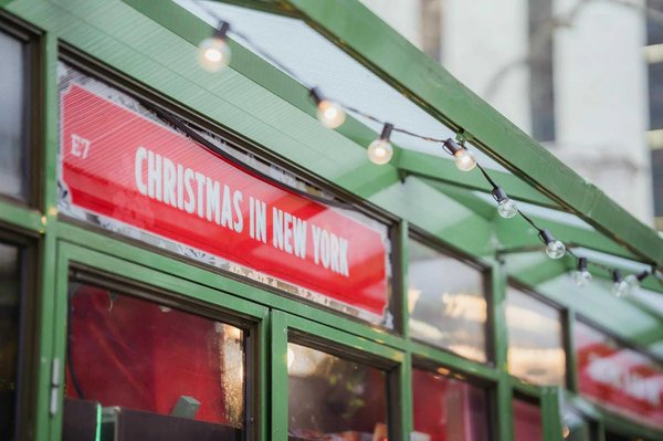 Mercatino di Natale a New York con decorazioni luminose e insegna rossa 'Christmas in New York'.